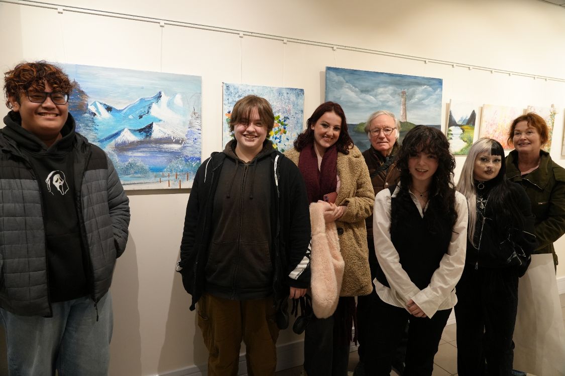 six art students and their tutor in front of some of their pictures which are on display at the Island  Arts Centre